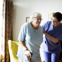 nurse-helping-senior-woman-stand-scaled.jpg